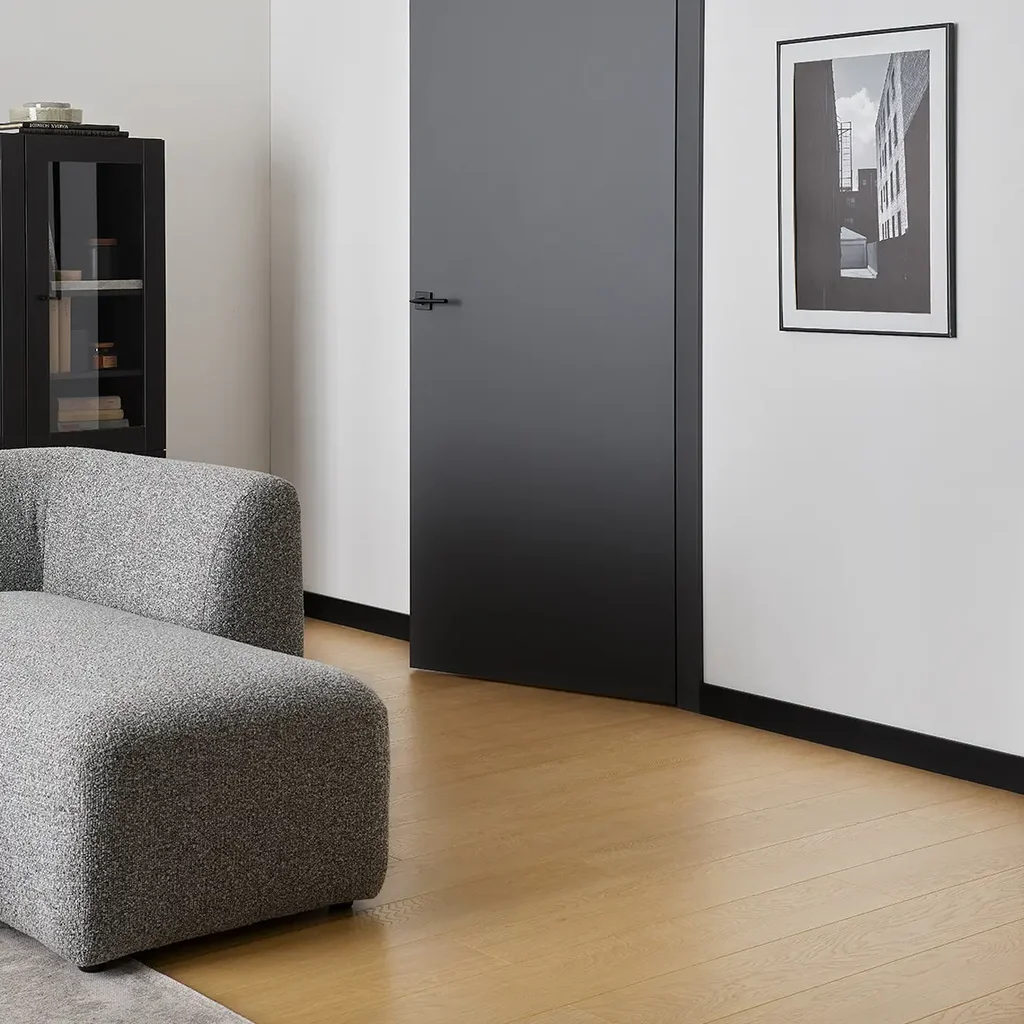 Stylowy salon z kontrastującą czarną listwą przypodłogową i jasną podłogą.